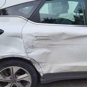 נזק לדלת צד של רכב לבן עם שריטות ושקעים