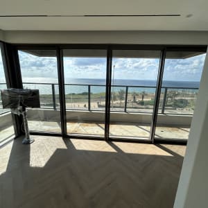 חדר עם רצפת עץ ונוף לים דרך חלונות גדולים