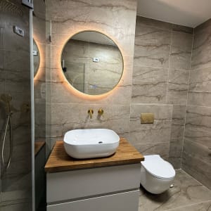 שיפוץ חדר אמבטיה עם כיור עגול ומראה מוארת