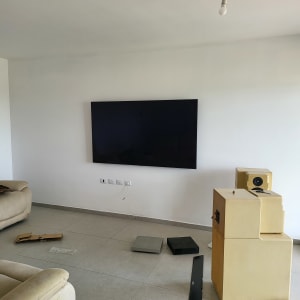 טלוויזיה תלויה על קיר, רמקולים וכלים על הרצפה