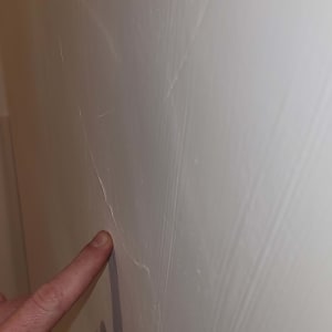 אצבע מצביעה על סדק בקיר לבן