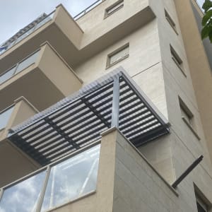 סוכך מתכת וזכוכית על מרפסת בניין