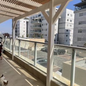 מרפסת עם פרגולה מעץ ונוף לבניינים