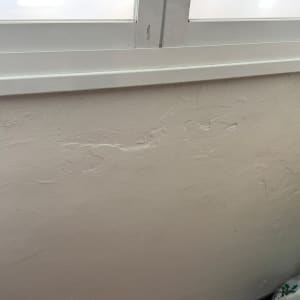 קיר עם סימני תיקון טיח ליד חלון