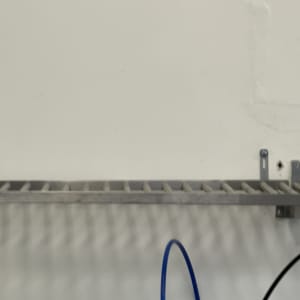 מדף מתכת מותקן על קיר עם כבלים חשמליים