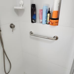 ידית אחיזה מתכתית מותקנת במקלחת לבנה