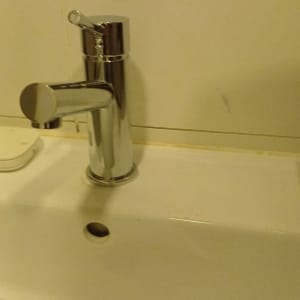 ברז כרום מבריק מותקן על כיור רחצה לבן