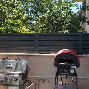 גדר אלומיניום הייטק אופקית בגוון אפור כהה בחצר בית