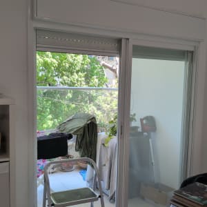 תריסים וחלון זכוכית במרפסת עם צמחייה בחוץ