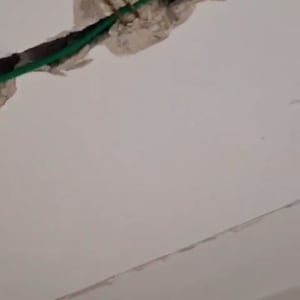 קיר גבס עם סדק וחוט ירוק חשוף