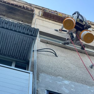 אדם תלוי על חבלים עם ציוד עבודה בגובה