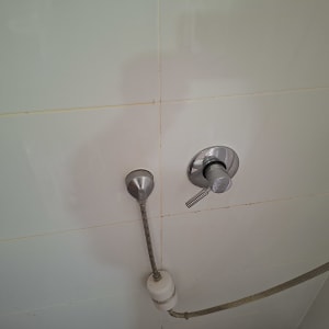 ברז מים ומקלחת על קיר אריחים