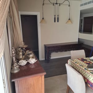 קיר גבס עם מנורה תלויה ושולחן עץ