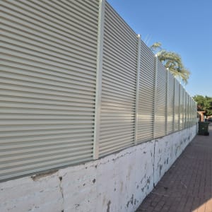גדר אלומיניום הייטק עם שלבים אופקיים המותקנת על חומת בטון