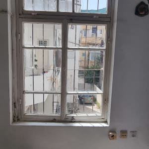 חלון עם סורגים ומבנים חיצוניים ברקע