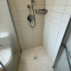 מקלחת עם אריחים לבנים וראש מקלחת מתכתי