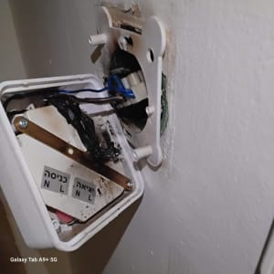 חוטי חשמל מחוברים לקופסת חיבורים בקיר