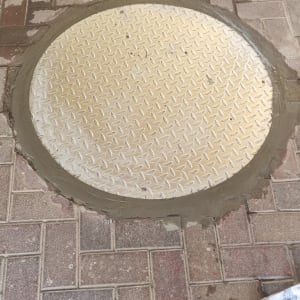 מכסה ביוב עגול על מדרכה מרוצפת