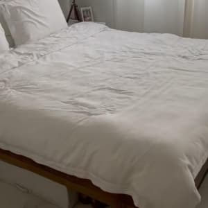 מיטה עם מצעים לבנים וחפצים מתחתיה