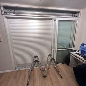 תריסים לבנים סגורים עם סולם מתכת בחדר