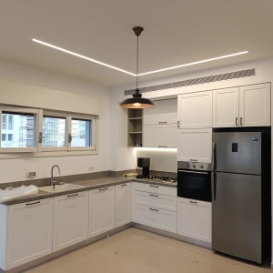 מטבח מודרני עם ארונות לבנים ומכשירי חשמל