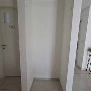נישה ריקה בין קירות גבס לבנים עם מוט מתכת מותקן בחלקה העליון