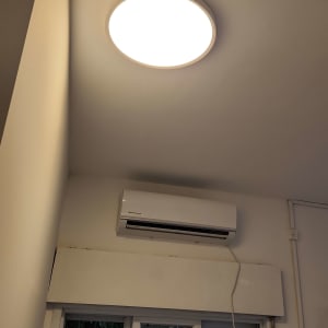 מזגן מותקן על קיר מעל חלון עם וילון