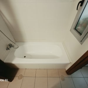 אמבטיה לבנה עם איטום סיליקון נקי סביב השוליים וחיפוי קיר מקרמיקה