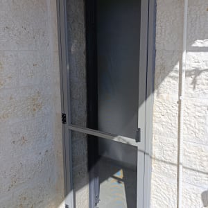 דלת אלומיניום אפורה עם רשת על מרפסת