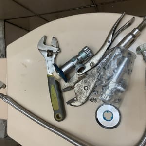 כלי עבודה וחלקי אינסטלציה על אסלה