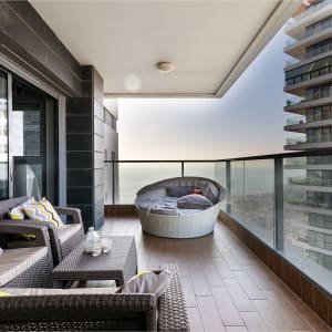 מרפסת עם ריהוט גן, כריות צבעוניות ונוף לים