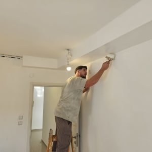 אדם צובע קיר בלבן בעזרת מברשת