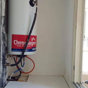 דוד שמש עם צינורות חיבורים על קיר לבן