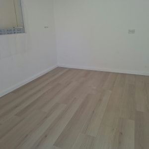התקנת פרקט למינציה בגוון עץ בהיר עם פנלים לבנים בחדר