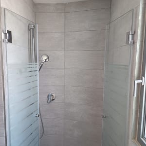 מקלחת עם דלתות זכוכית וראש מקלחת כסוף