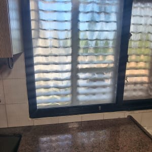 חלון זכוכית במטבח עם משטח שיש וארונות עץ