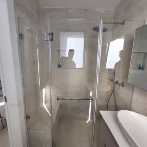 מקלחון זכוכית עם ראש מקלחת ומדף קטן