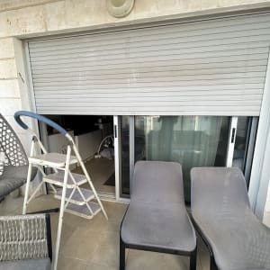מרפסת עם תריס סגור, סולם וכיסאות ישיבה
