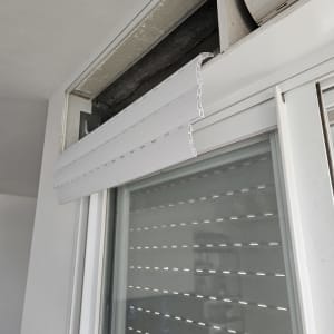 תריס גלילה לבן פתוח חלקית עם מנגנון חשוף