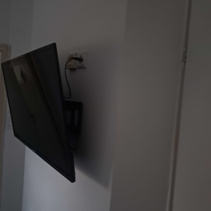 טלוויזיה תלויה על קיר עם כבל חשמל