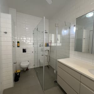 חדר אמבטיה עם מקלחון זכוכית, כיור ומראה