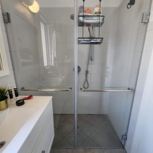 מקלחת עם דלתות זכוכית, מדף עם מוצרי רחצה