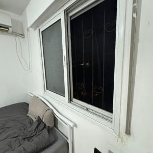 חלון עם סורגים בחדר שינה, מיטה ליד החלון