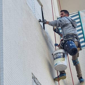 אדם בעבודות גובה עם ציוד בטיחות על קיר בניין