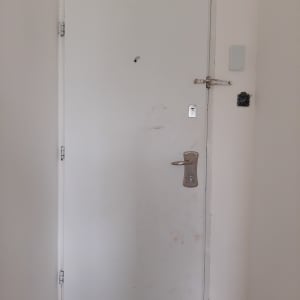 דלת לבנה עם ידית ומנעול בריח עליון