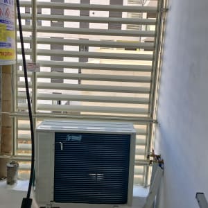 יחידת מיזוג אוויר מותקנת ליד קיר עם צינורות וחיבורים