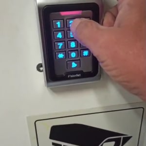 יד לוחצת על מקלדת אינטרקום עם תאורה כחולה