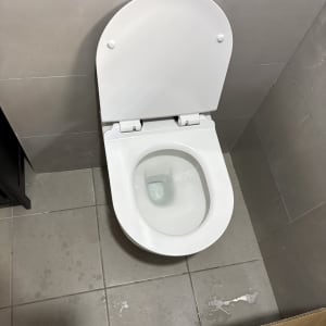 אסלה לבנה מותקנת בחדר אמבטיה עם רצפת אריחים אפורה