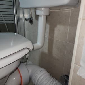 אסלה עם חיבורי צנרת בחדר אמבטיה