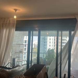 וילונות תלויים על חלון זכוכית גדול עם נוף עירוני